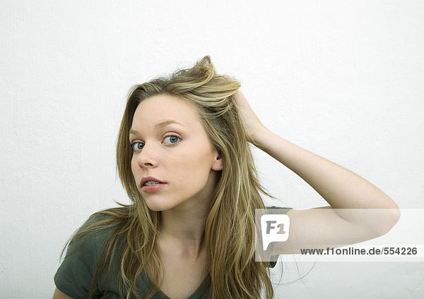Teenagermädchen schiebt Haare zurück und schaut in die Kamera  Portrait