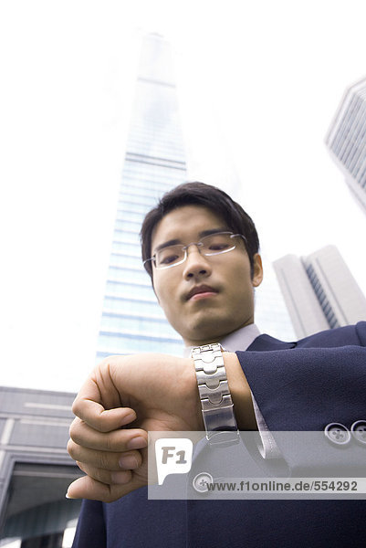 Geschäftsmann steht auf Armbanduhr  Wolkenkratzer im Hintergrund