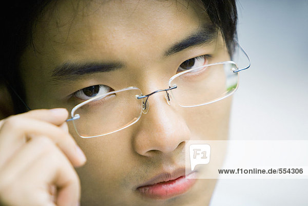 Man adjusting glasses  looking at camera  close-up