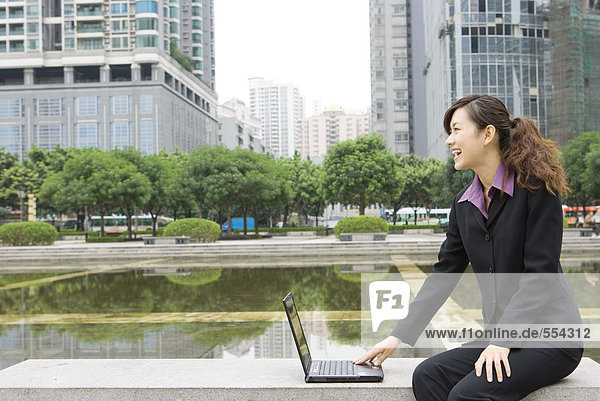 Geschäftsfrau mit Laptop am Wasser im Büropark