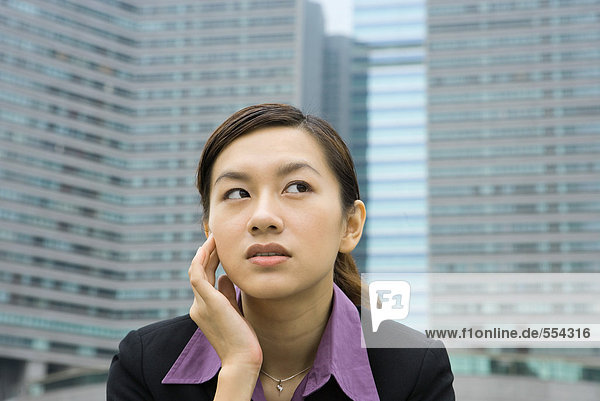 Businesswoman holding head and looking away  high rises in background