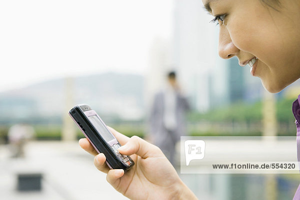 Geschäftsfrau mit Messaging-Telefon  lächelnd  Nahaufnahme  Seitenansicht