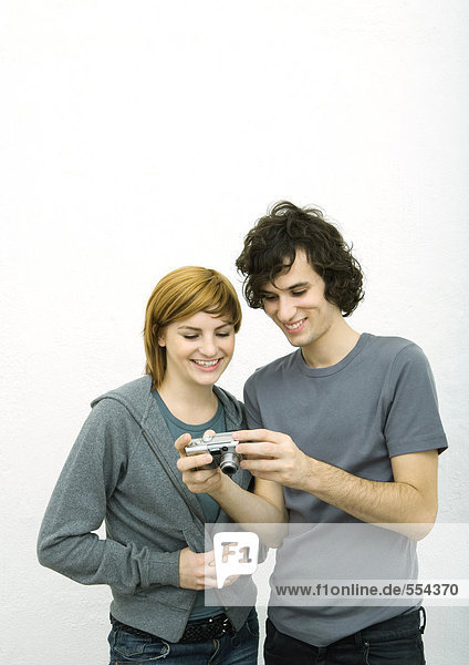 Junger Mann zeigt junge Frau Digitalkamera