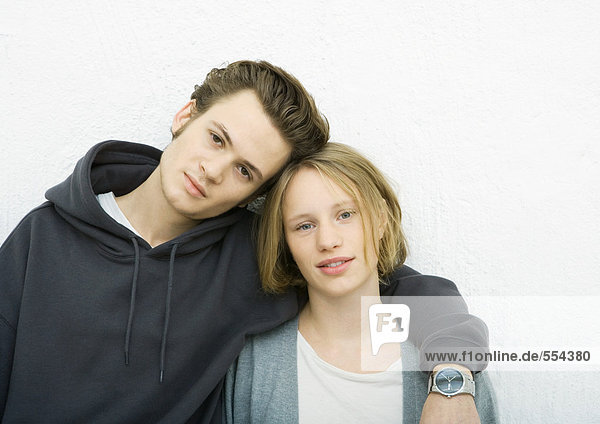 Young couple leaning against wall  looking at camera  portrait