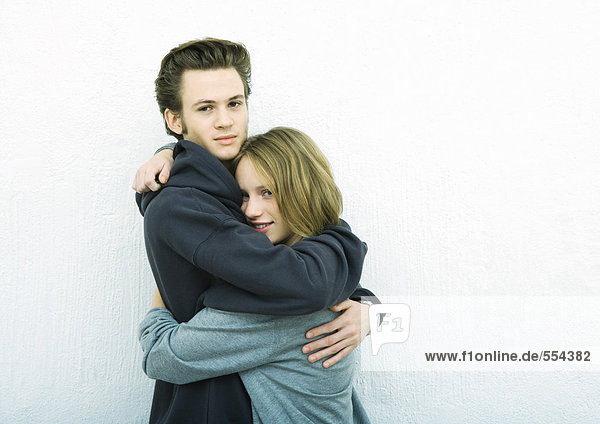 Young couple embracing  looking at camera  white background