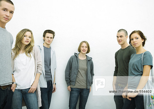 Group of young adult and teenage friends  looking at camera  three quarter length  white background