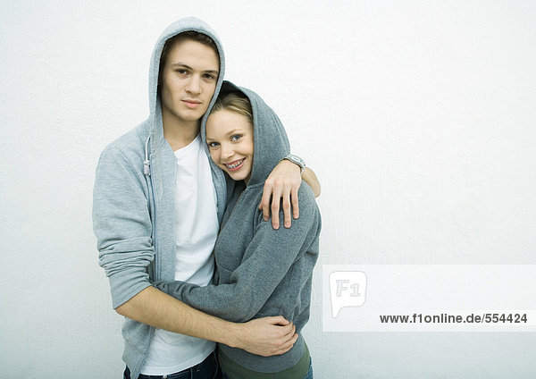 Young couple wearing hooded sweatshirts  embracing
