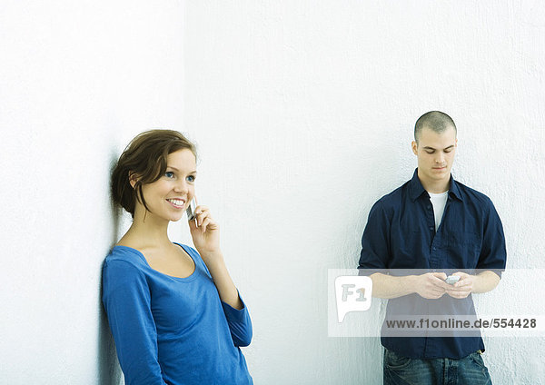 Junger Mann und junge Frau mit Mobiltelefonen