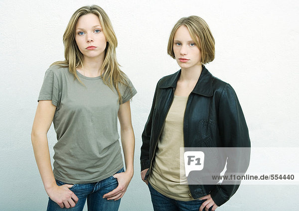 Teenagermädchen stehen Seite an Seite mit den Händen auf der Hüfte  schauen in die Kamera  Porträt