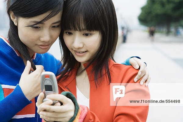 Zwei junge Frauen  die zusammen auf das Handy schauen.