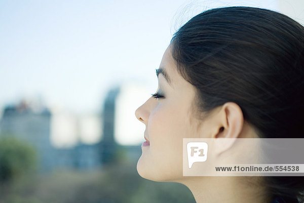 Woman closing eyes  close-up  city in blurred background