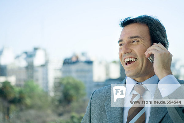 Geschäftsmann mit Handy und Lachen  Skyline im Hintergrund
