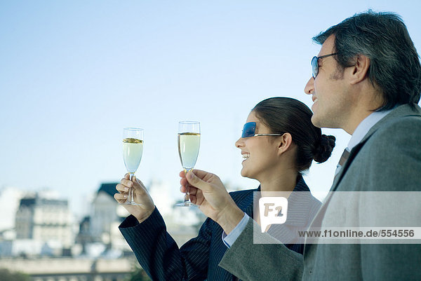 Business partners holding up glasses of champagne  skyline in background