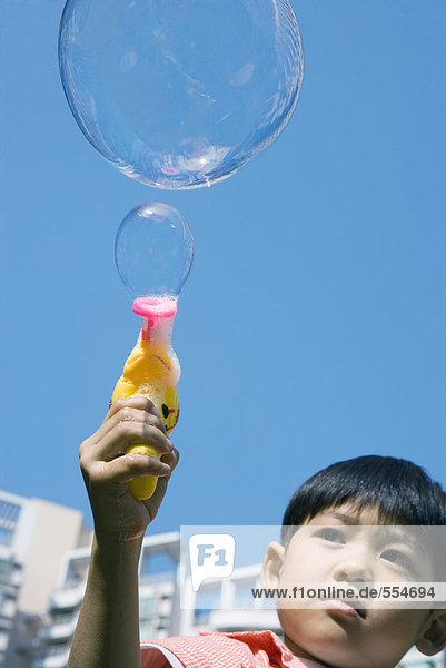 Boy making bubbles with bubble gun