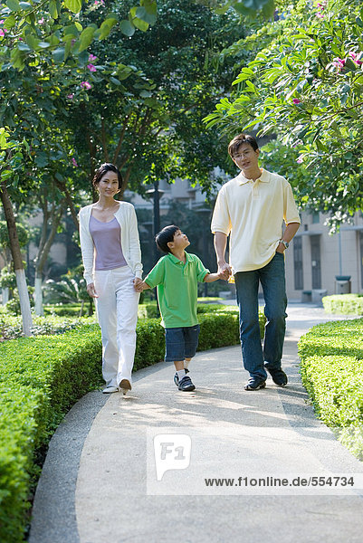 Boy walking hand in hand with parents  full length