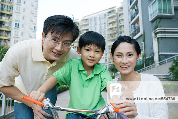 Boy on bicycle  between parents  portrait