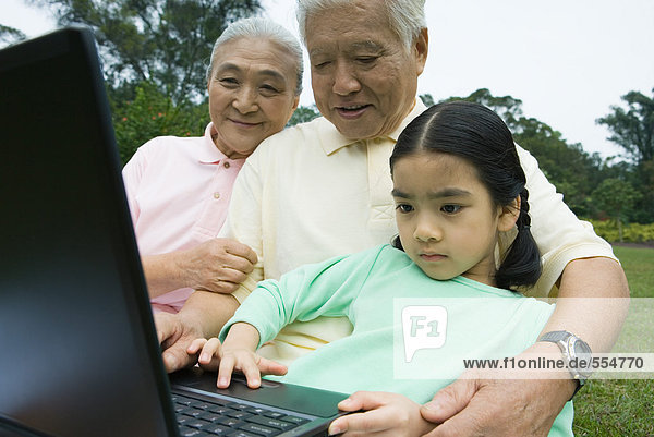 Mädchen und Großeltern mit Laptop
