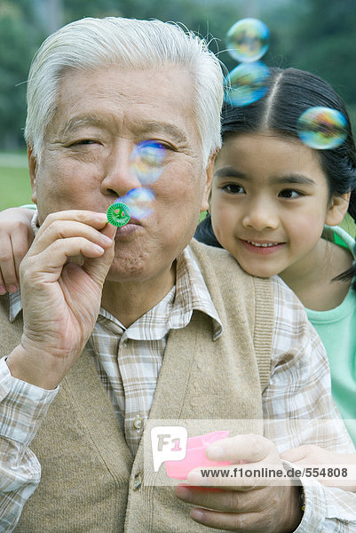Mädchen mit Großvater bläst Blasen