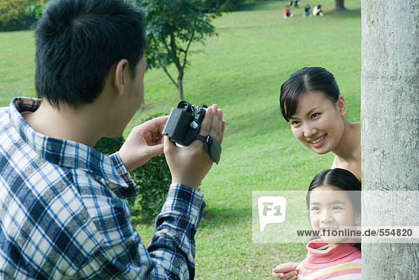 Mann filmt Frau und Tochter im Park mit Videokamera