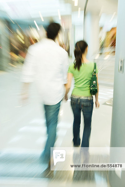 Couple walking in shopping mall  rear view  blurred motion