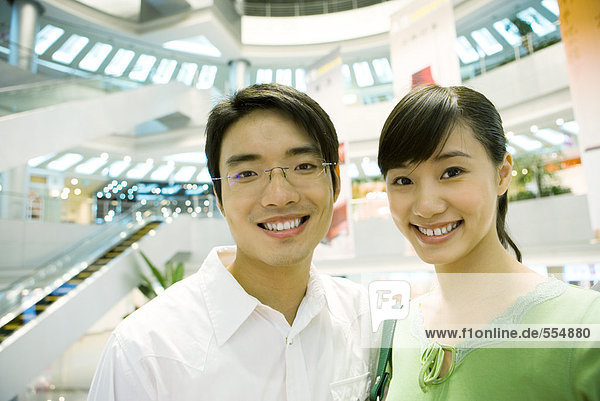 Couple in shopping mall  smiling at camera  portrait