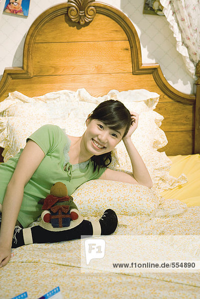 Young woman reclining on bed  smiling at camera