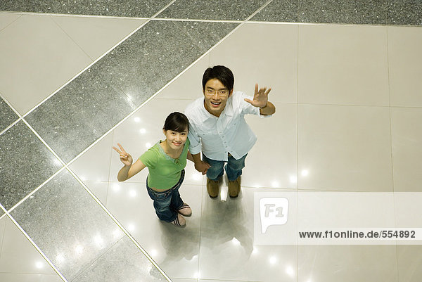 Young couple standing on star pattern  looking up at camera  high angle view