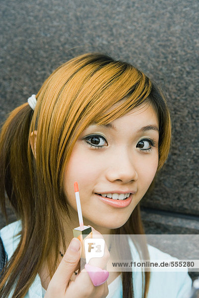 Teenage girl holding lipgloss wand mouth