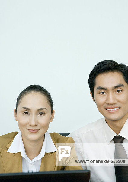 Businessman and businesswoman side by side  smiling at camera