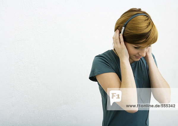 Young woman listening to headphones  white background
