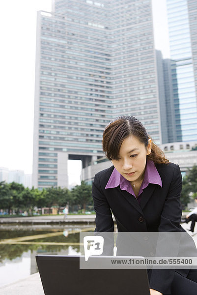 Junge Geschäftsfrau mit Laptop im Büropark