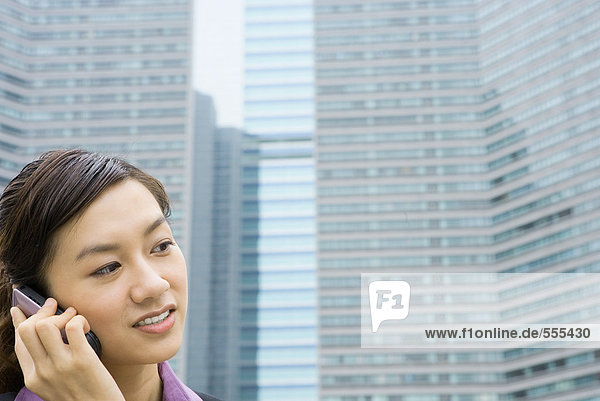 Junge Geschäftsfrau mit Handy  Bürogebäude im Hintergrund