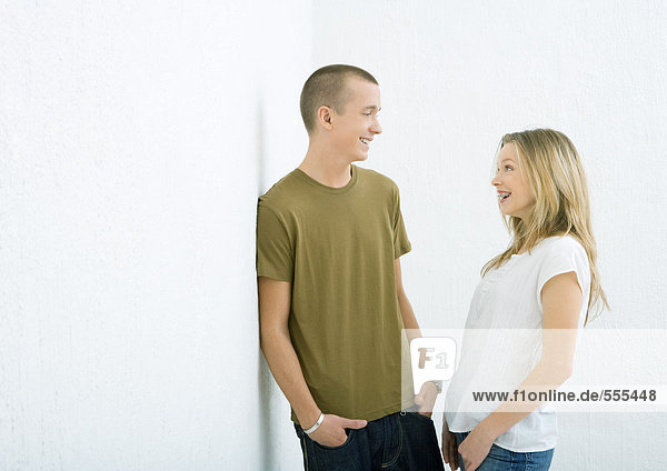 Junger Mann und Frau lächeln sich an  Hände in den Taschen.