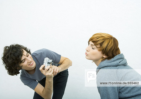 Young woman puckering while young male friend takes photo