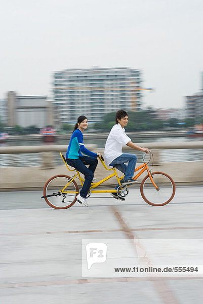 Young couple riding tandem bicycle