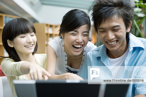 Drei Freunde  die den Computer benutzen  lachend.