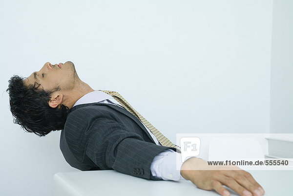 Businessman sitting with head back and eyes closed