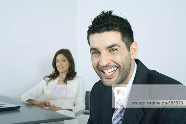 Businessman laughing  colleague in background