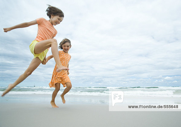 Zwei Mädchen beim Laufen und Springen am Strand