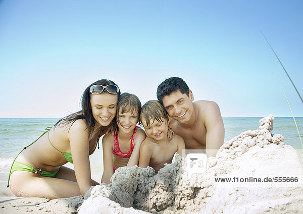 Familie sitzt am Strand in der Nähe von Sandhaufen  Portrait