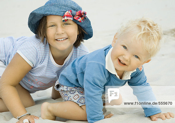 Mädchen und Kleinkind am Strand  lächelnd vor der Kamera