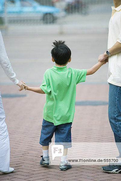 Boy holding parents' hands