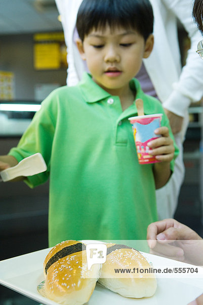 Junge schaut auf ein Tablett mit Lebensmitteln