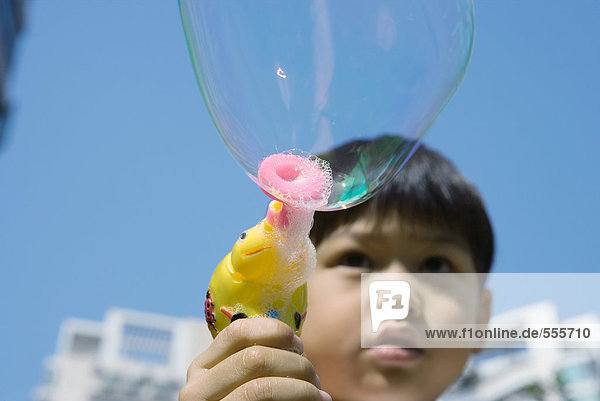Junge macht Blasen mit Blasenstab