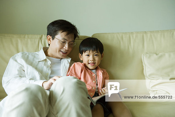 Vater und Sohn sitzen auf dem Sofa  lesen Buch
