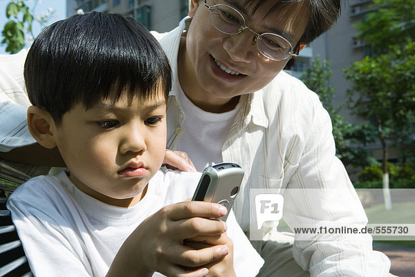 Vater und Sohn  Junge schaut auf Handy
