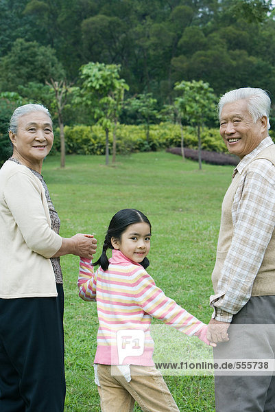 Girl walking hand in hand with grandparents