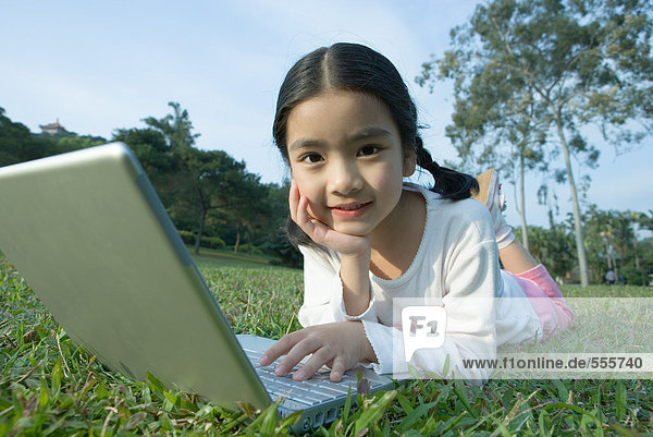 Mädchen auf Rasen liegend mit Laptop