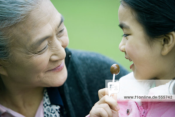Mädchen beim Lolli essen  Großmutter ansehen  Nahaufnahme