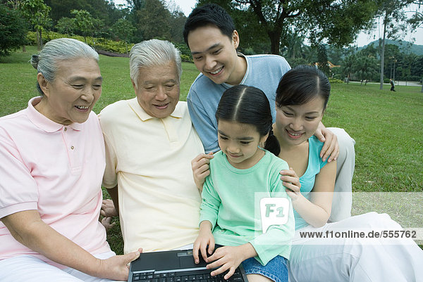 Drei-Generationen-Familie,  mit Laptop im Park